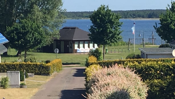 A pathway leading to a building with a view of a lake. - Captains-TERRACE- Photovoltaic- Fireplace-large quiet terrace (Göhren-Lebbin)