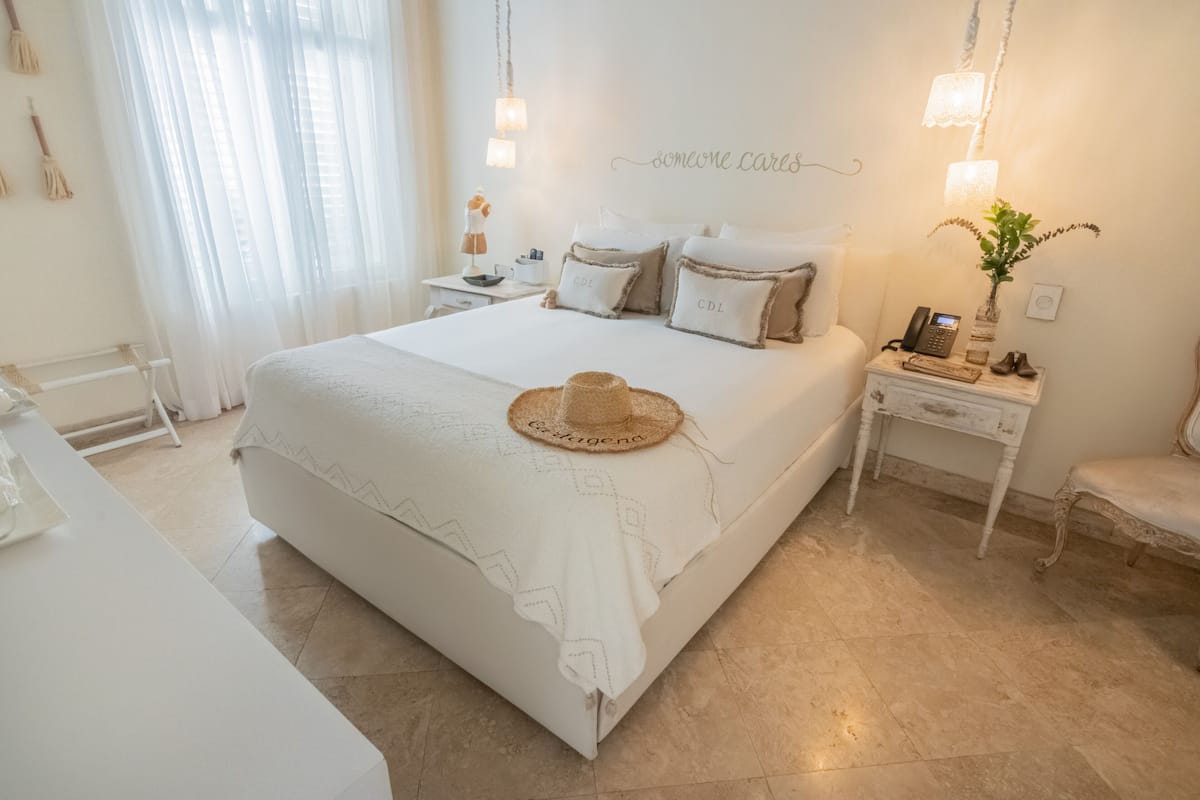 Ein ordentlich eingerichtetes Schlafzimmer mit Bett, Nachttischen und einem Sessel.