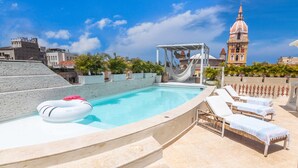 A rooftop pool with lounge chairs, a hammock, and a view of a historic tower. -  Casa DiLuca Cartagena Hotel Boutique (Cartagena)