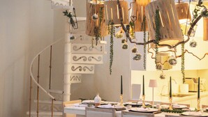 A dining area with a white table set for four, a white sofa, and a spiral staircase in the background. -  Casa DiLuca Cartagena Hotel Boutique (Cartagena)