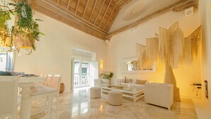A spacious living area with a high ceiling, a dining table with chairs, a sofa, and a coffee table. -  Casa DiLuca Cartagena Hotel Boutique (Cartagena)
