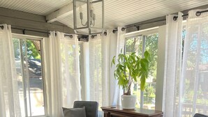 Una sala de estar acogedora con chimenea, asientos confortables y un amplio ventanal con cortinas.