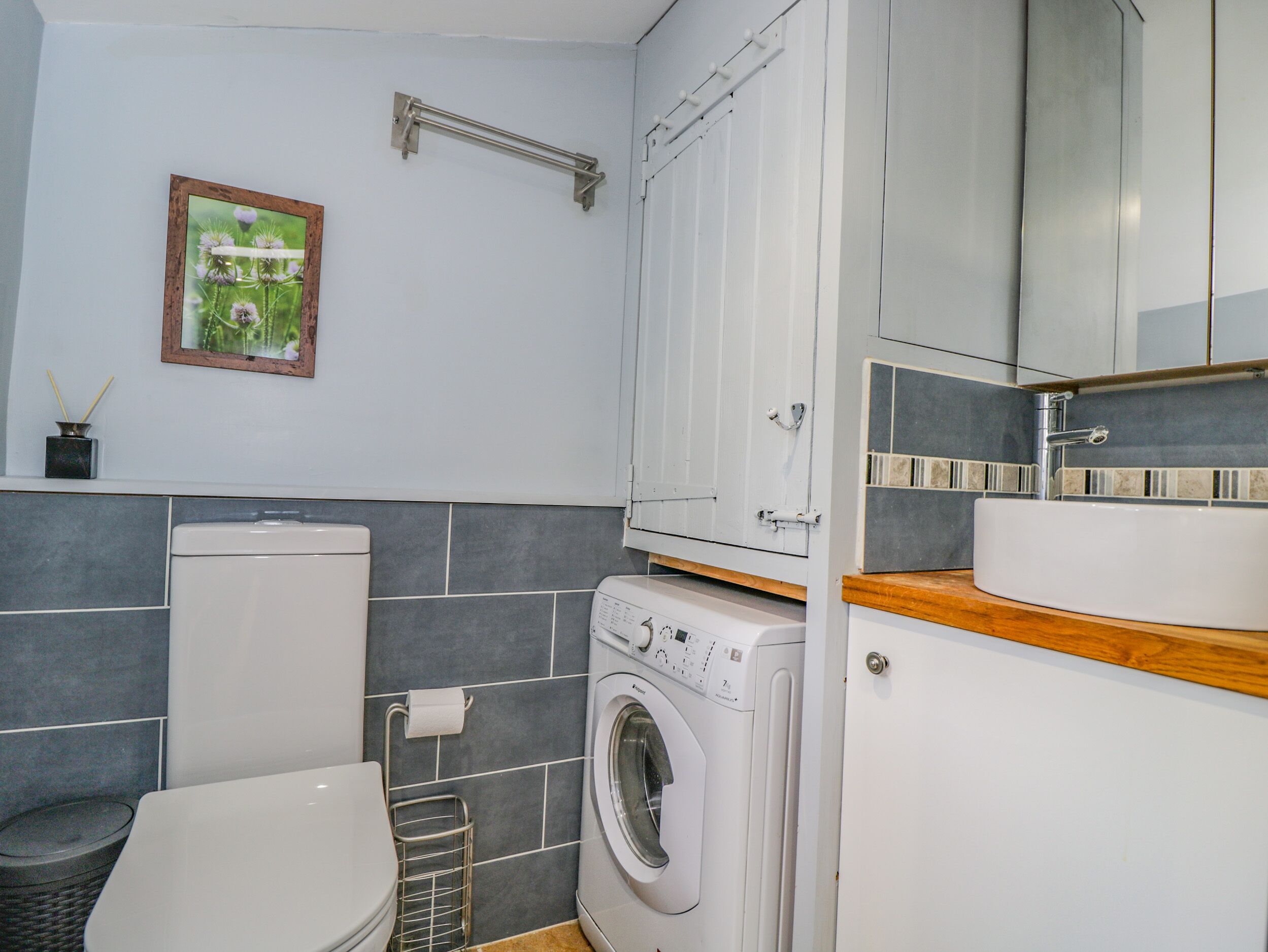 Een kleine badkamer met toilet, wasmachine en wastafel.