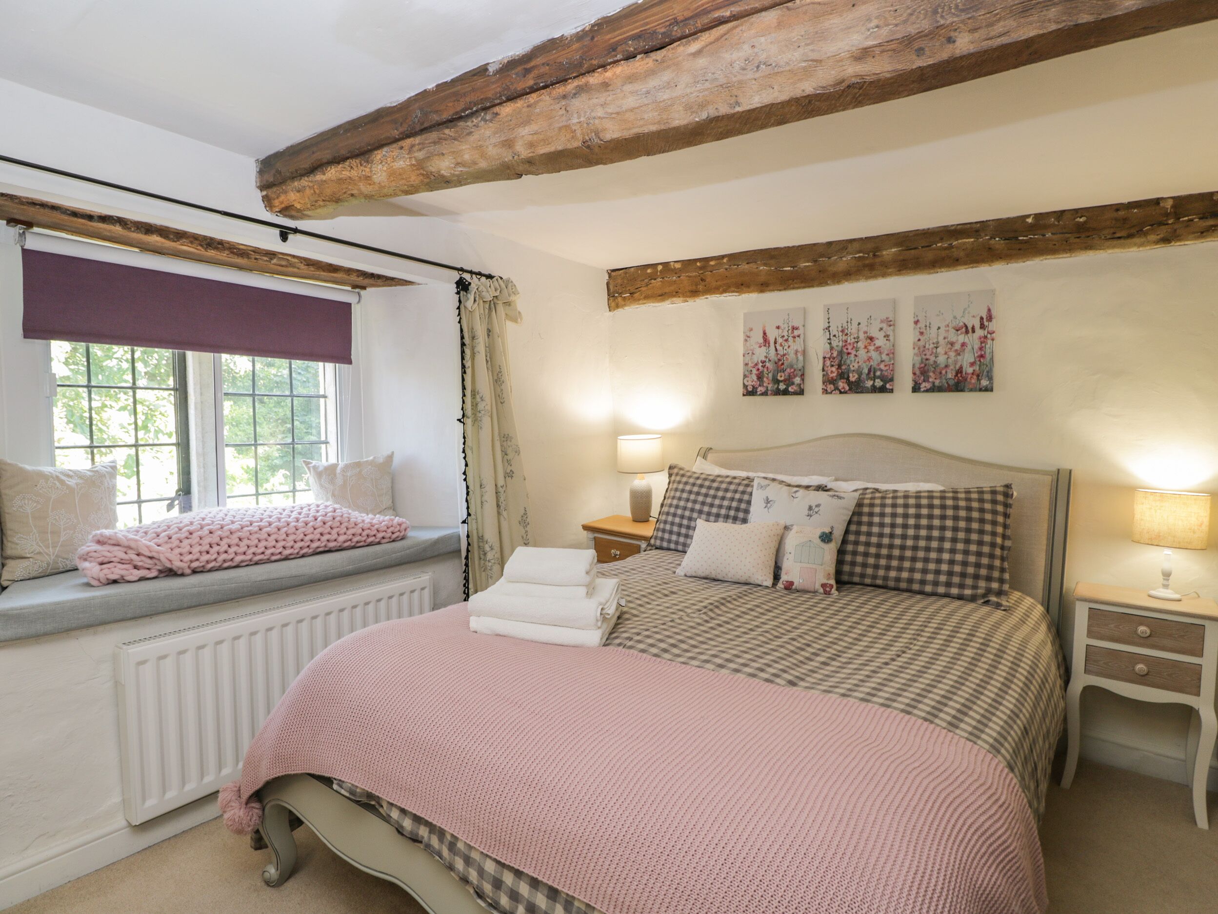 A bedroom with a large bed, a window seat, and a radiator.