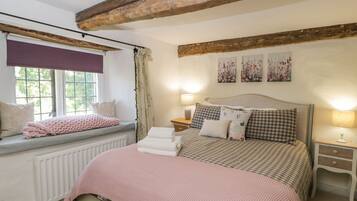 A bedroom with a large bed, a window seat, and a radiator.