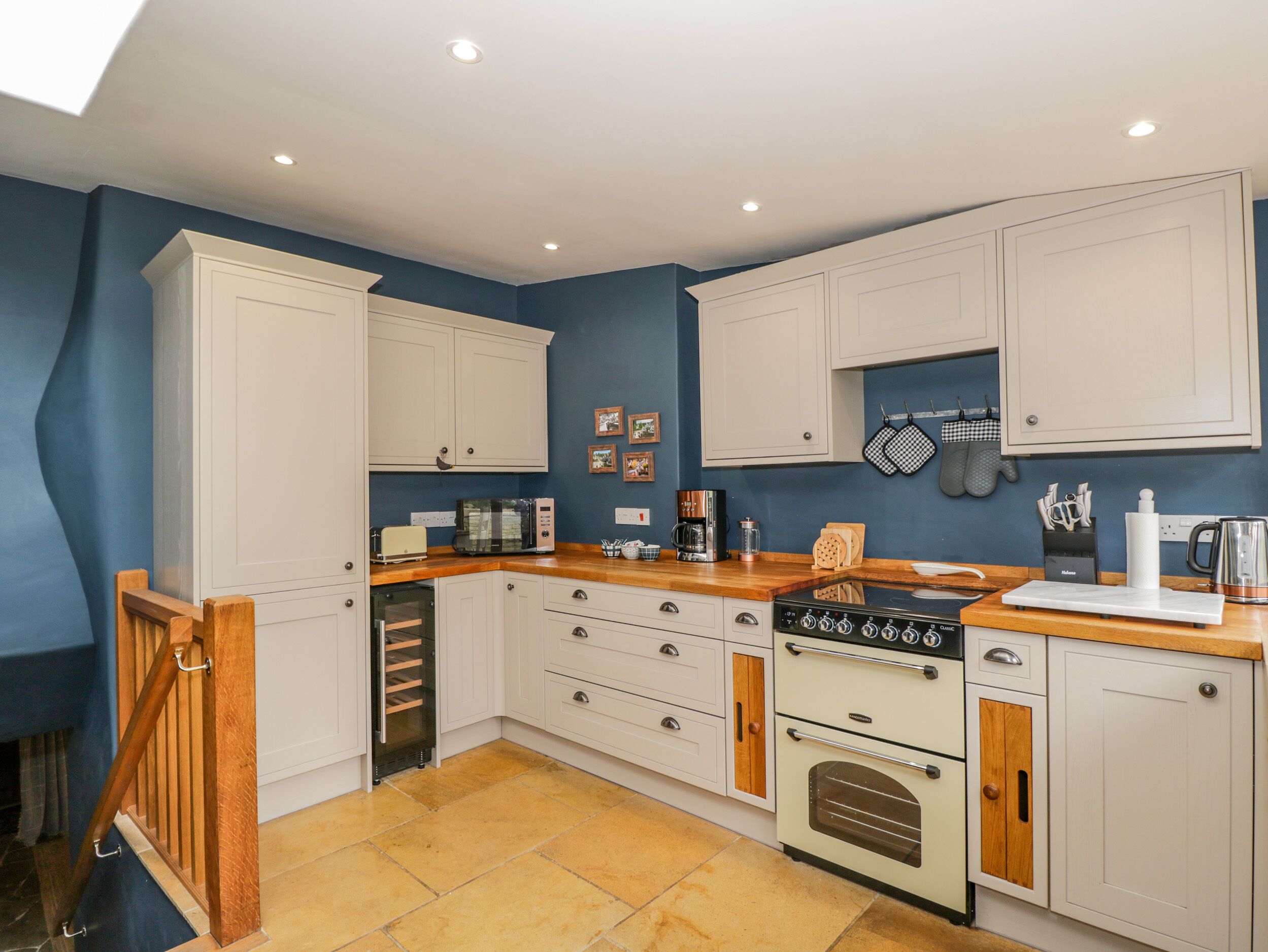 A kitchen with white cabinets, a wooden countertop, a stove, and a coffee maker.