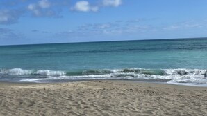 Une plage à l’eau d’un bleu limpide et au rivage sablonneux.