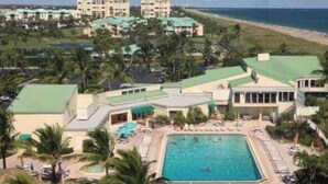 Un complexe hôtelier doté d’une piscine centrale, de plusieurs bâtiments et d’une plage en arrière-plan.