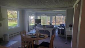 Un comedor con una mesa preparada para cuatro, un sofá y un televisor al fondo.