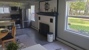 Una cocina moderna con electrodomésticos de acero inoxidable, una chimenea y un amplio ventanal con vistas a un jardín.