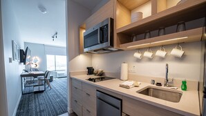 A modern kitchen with a built-in microwave, a sink, and a coffee maker. There is a dining area with a table and chairs visible in the background. - TownePlace Suites by Marriott Las Vegas North I-15 (Las Vegas)