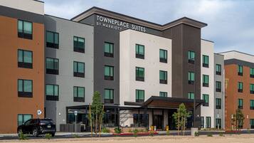 Un hôtel à plusieurs étages, avec une enseigne indiquant « Towneplace Suites by Marriott » et un parking où est stationné un SUV noir.
