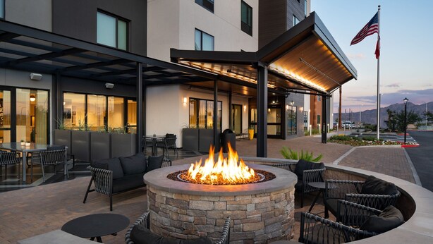 An outdoor seating area with a fire pit, stone seating, and a covered patio. - TownePlace Suites by Marriott Las Vegas North I-15 (Las Vegas)