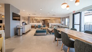 A modern hotel lobby with a dining area, seating, and a kitchen. - TownePlace Suites by Marriott Las Vegas North I-15 (Las Vegas)