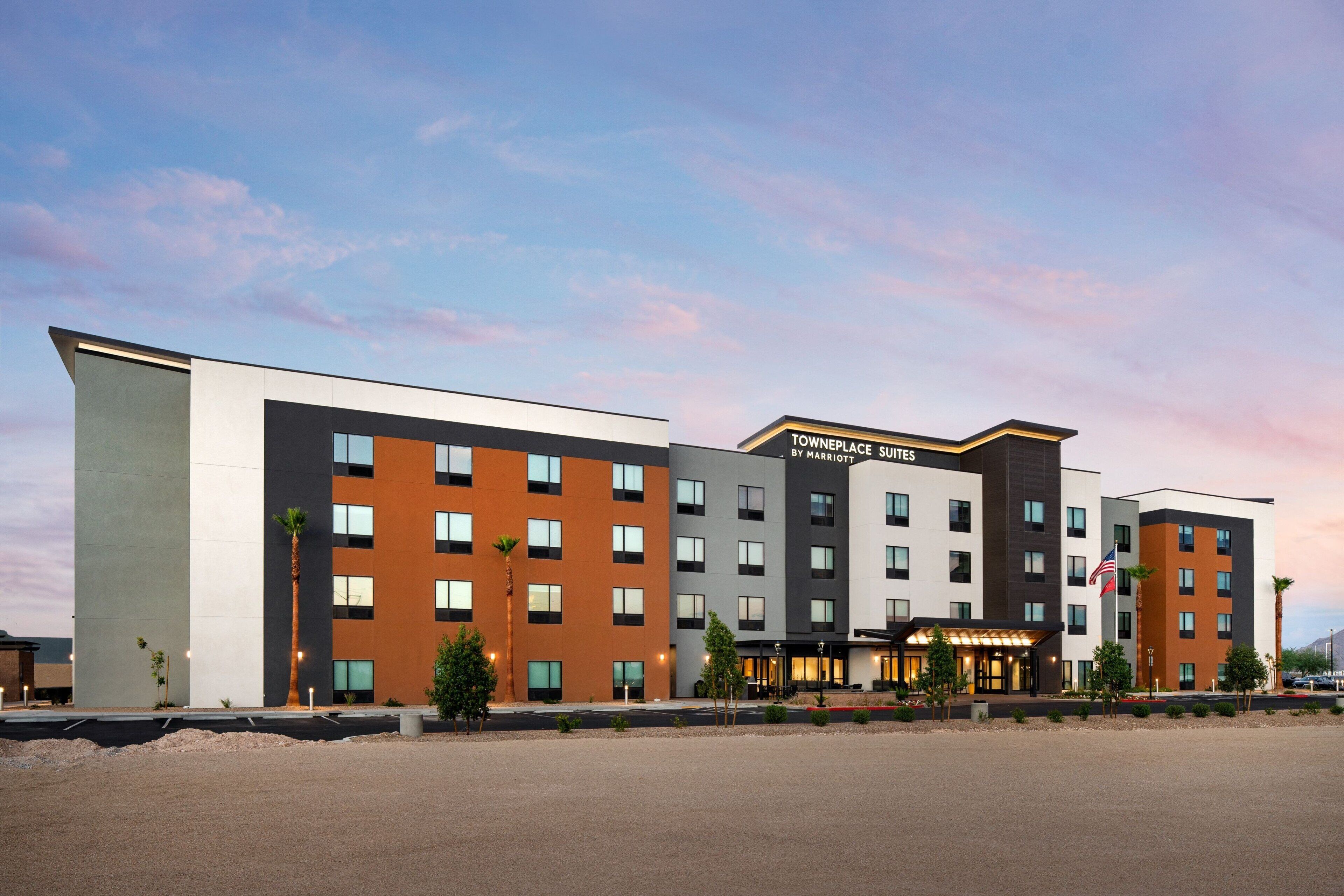 Un hotel de varios pisos con un diseño moderno, que presenta una combinación de techos planos y en ángulo, y un letrero llamativo para 'Townplace by Marriott Suites'.