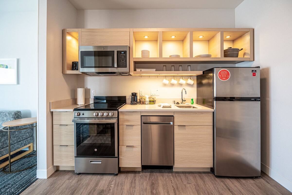 A compact kitchen with a microwave, stove, dishwasher, and refrigerator.