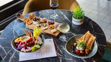 A marble table with a variety of food items, including cheese, fruits, and bread, accompanied by wine glasses and a menu.