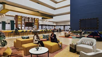 Eine großzügige Lobby mit Sitzbereichen, einer Bar und einem großen Bildschirm.