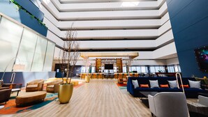 Un hall espacioso con techo alto, asientos modernos y una zona de bar central.