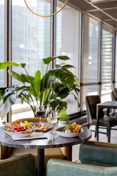 A hotel room with a large bed, a desk with a TV, a chair, and a view of a cityscape through large windows. at voco Chicago Downtown - Riverwalk by IHG