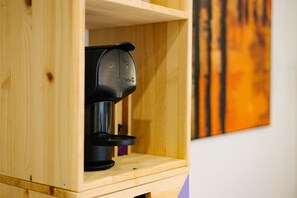 Een koffieapparaat in een houten kast met een plank erboven.