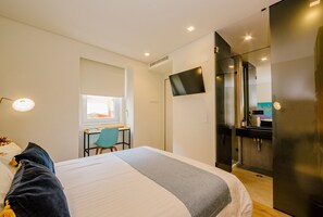 Una habitación de hotel moderna con cama, escritorio, silla y televisor de pantalla plana.