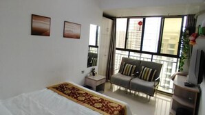 Una habitació d'hotel amb llit, sofà, televisió i grans finestres.