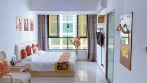 Una habitació d'hotel amb llit, una cadira, televisió i finestra amb cortines.