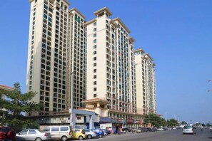 A multi-story hotel with a central courtyard, surrounded by parked cars and a clear sky. - Kaisheng Express Hotel (Beihai)
