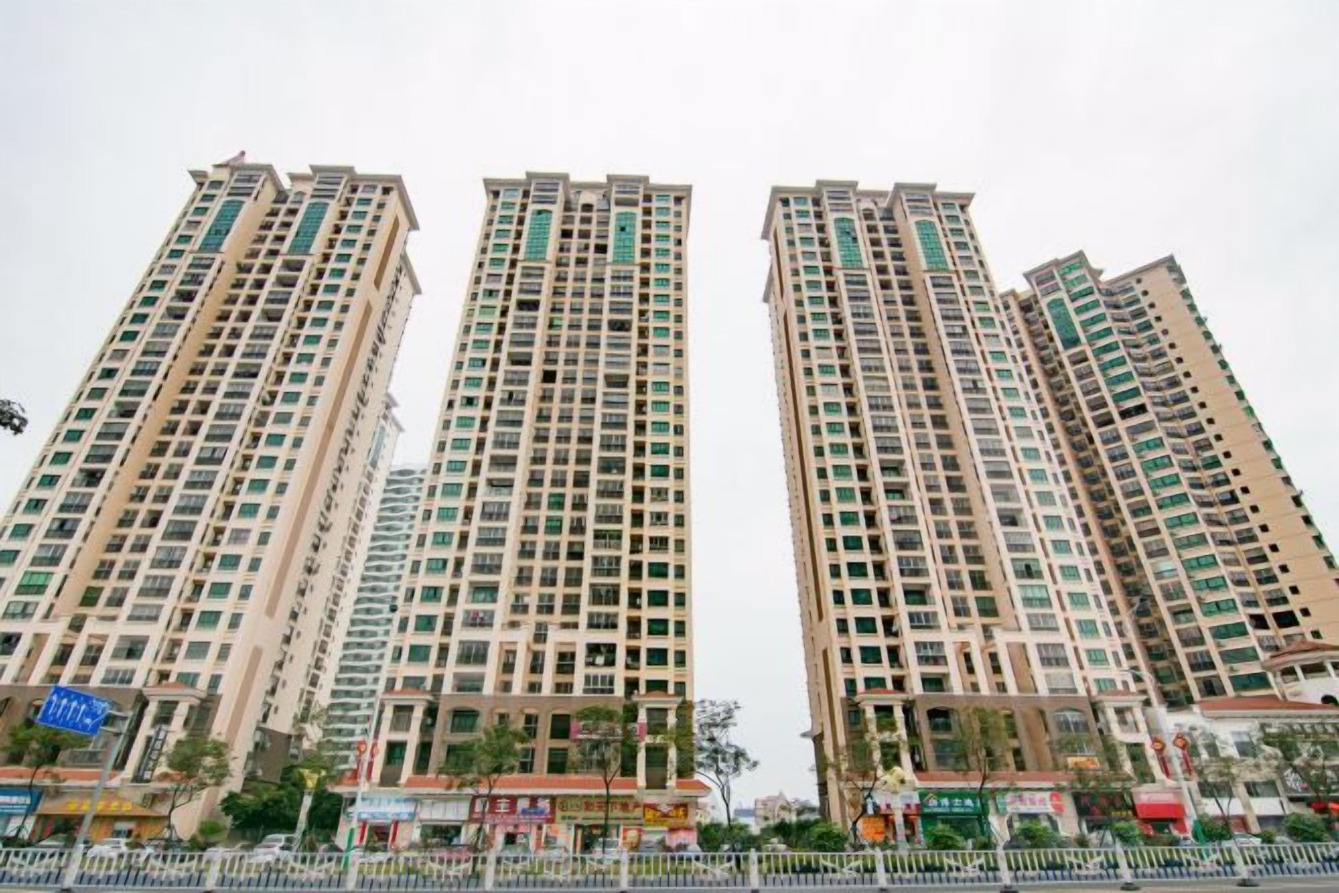 A high-rise residential building with multiple floors, balconies, and a gated entrance.