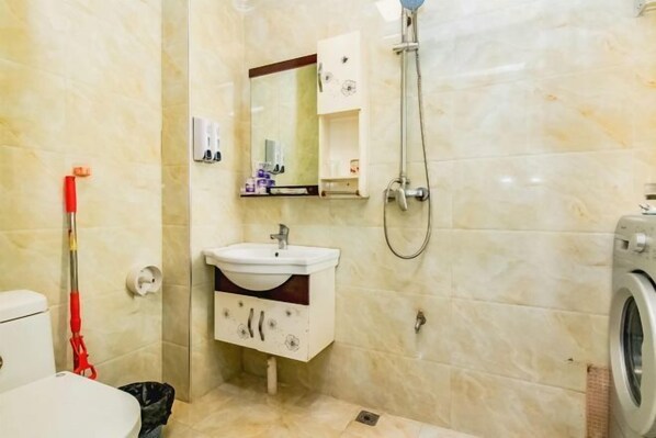 Ein Badezimmer mit Waschbecken, Spiegel, Dusche und Waschmaschine.