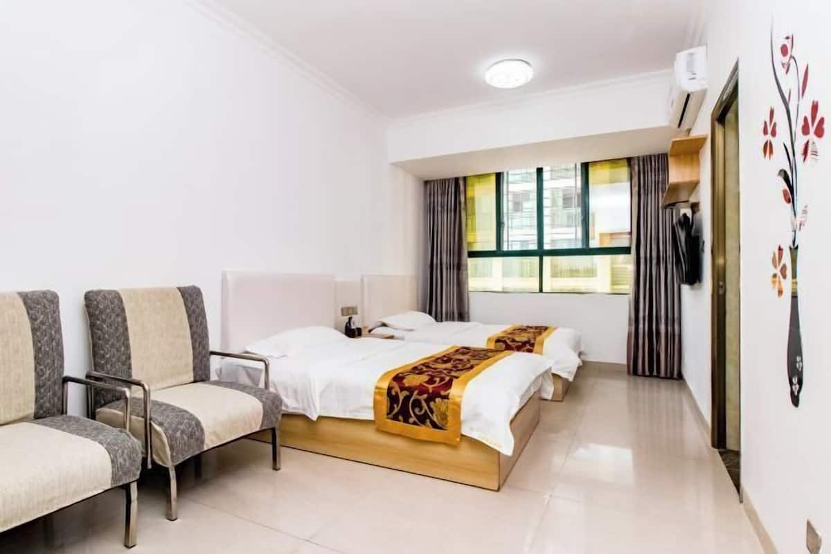 A hotel room with two beds, a sofa, a TV, and a window with curtains.