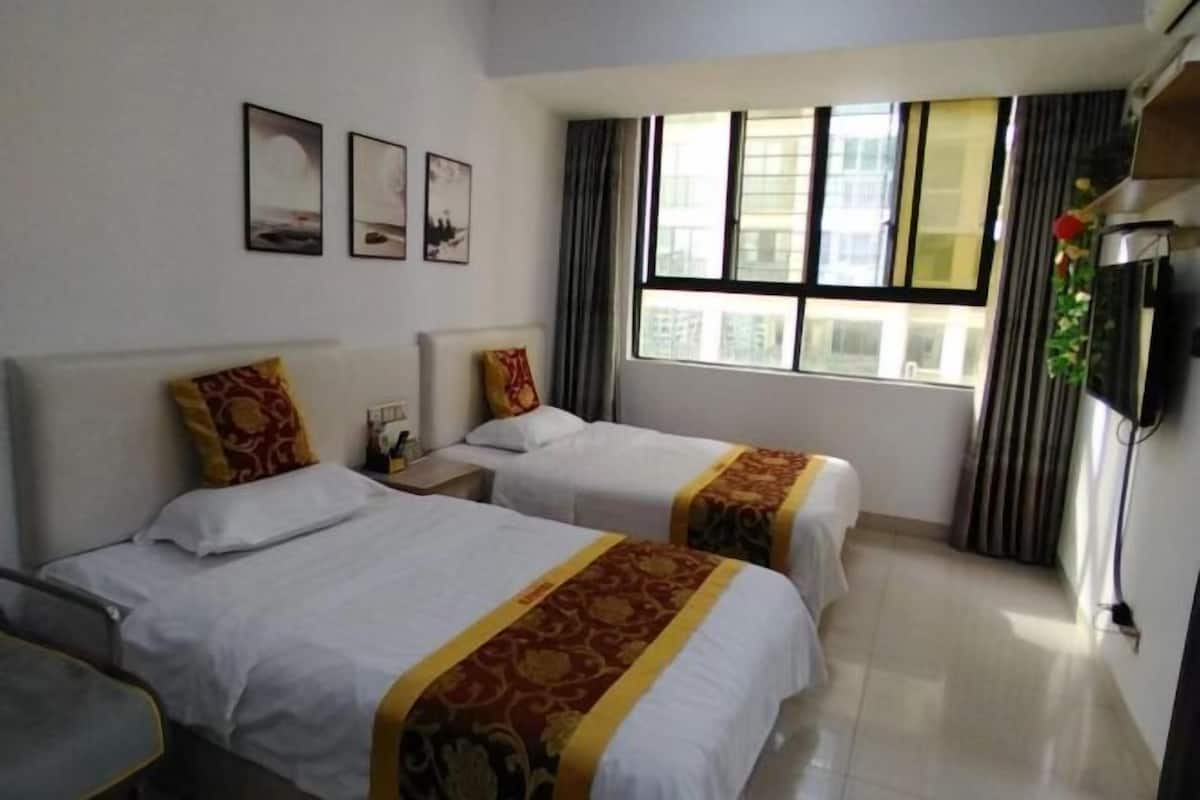 A hotel room with two beds, a TV, a window with curtains, and wall art.