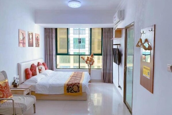 Relax in a spacious room with a large bed and a window offering a view of a nearby building.
