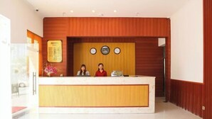 Taulell de recepció amb dos empleats, un rellotge i una pissarra amb el menú.