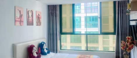 Una habitación de hotel con una cama, una mesita de noche, una ventana con cortinas y una obra de arte en la pared.