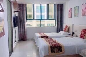 Habitación de hotel con dos camas, televisión y ventana con cortinas.
