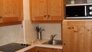 A compact kitchen with wooden cabinets, a stainless steel sink, and a microwave. - 150m from ski slopes, 2nd floor, view swimming pool, fitness, swimming pool, balcony, tv, ski locker (Lanslebourg-Mont-Cenis)