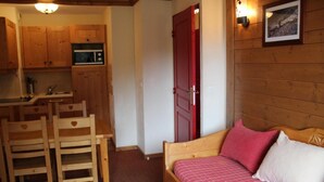 A compact room with a wooden bed, a small kitchenette, and a dining area with wooden chairs. - 150m from ski slopes, 2nd floor, view swimming pool, fitness, swimming pool, balcony, tv, ski locker (Lanslebourg-Mont-Cenis)