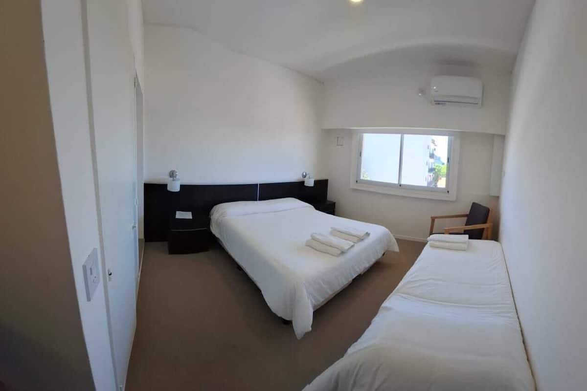 A bedroom with two beds, a window, and an air conditioning unit.