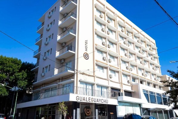 A multi-story hotel with balconies, air conditioning units, and a clear sky.