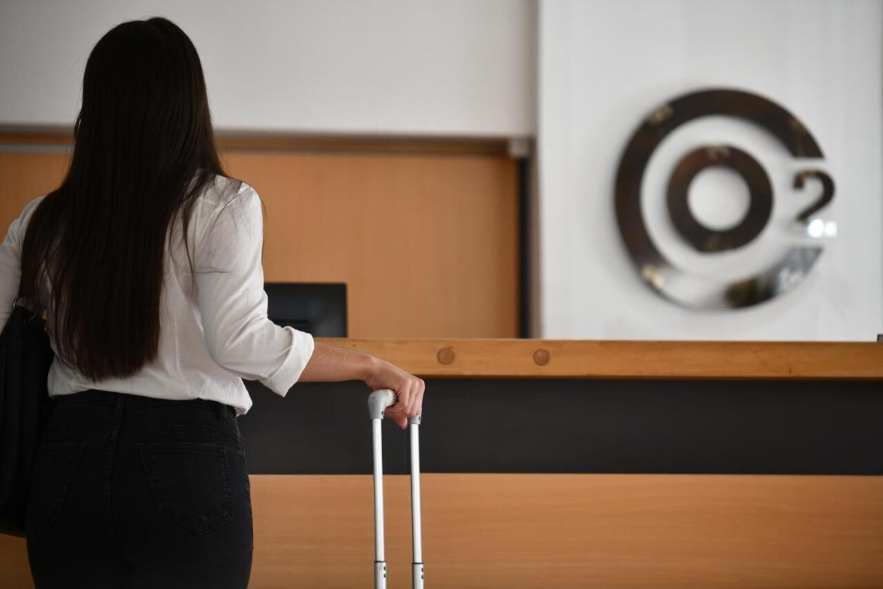 Eine Person mit Koffer am Empfangstisch in der Hotelhalle.