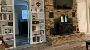 A living room with a fireplace, bookshelves, and a television. - Clair de Lune, Lake Front on Lake Palestine  (Chandler)