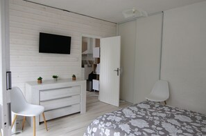 Ein Schlafzimmer mit einem Bett, einem Schminktisch, einem Fernseher und einer Tür zu einem Badezimmer.