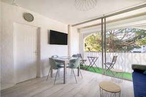 Ein Balkon mit Tisch, Stühlen, einer Couch und einem an der Wand befestigten Fernseher.