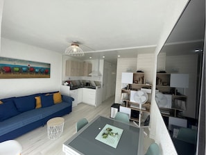 Ein modernes Wohnzimmer mit einer Couch, einem Esstisch und einer Küchenzeile.