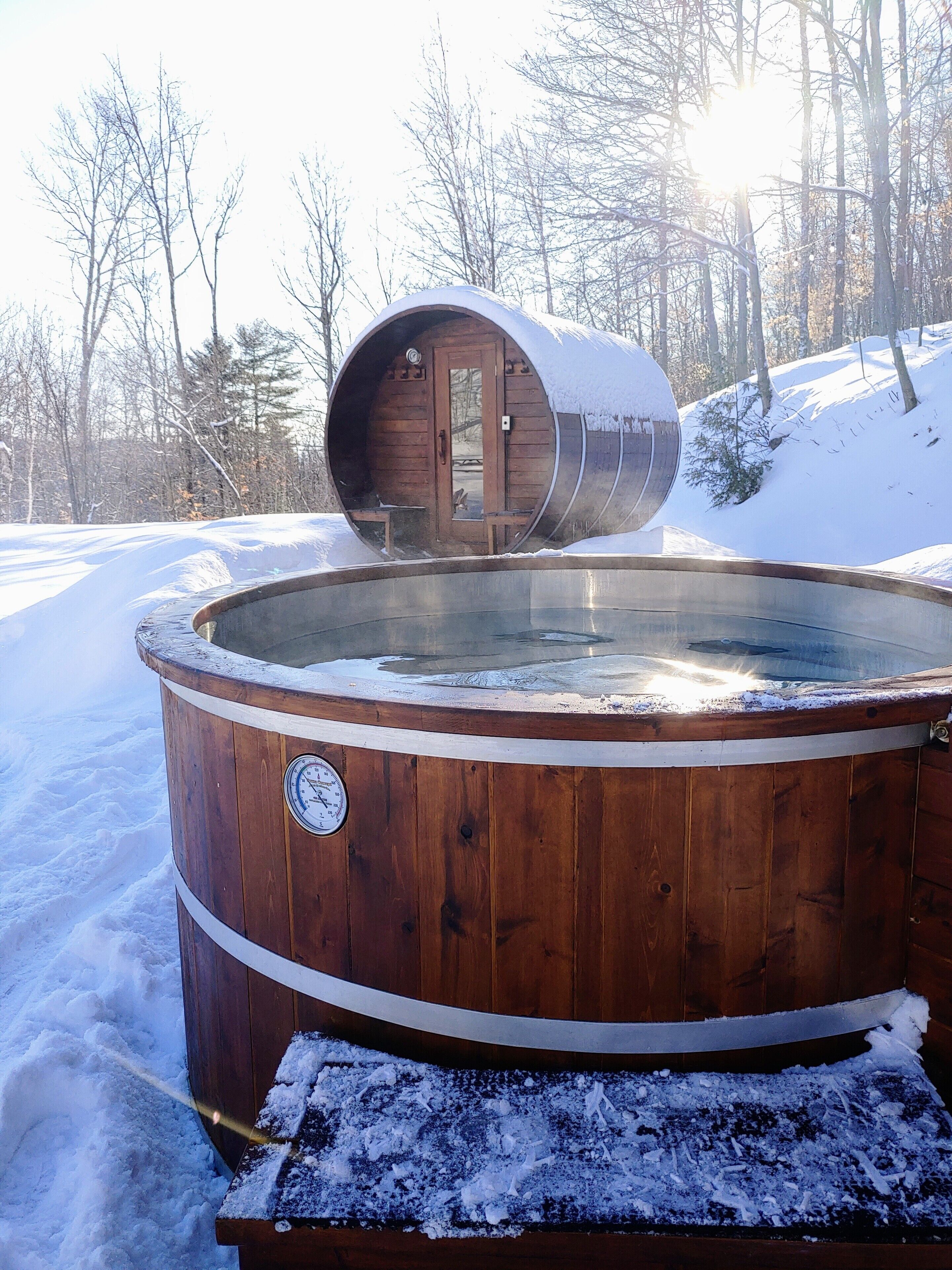 Ein hölzernes Whirlpool mit Holztür, umgeben von Schnee.