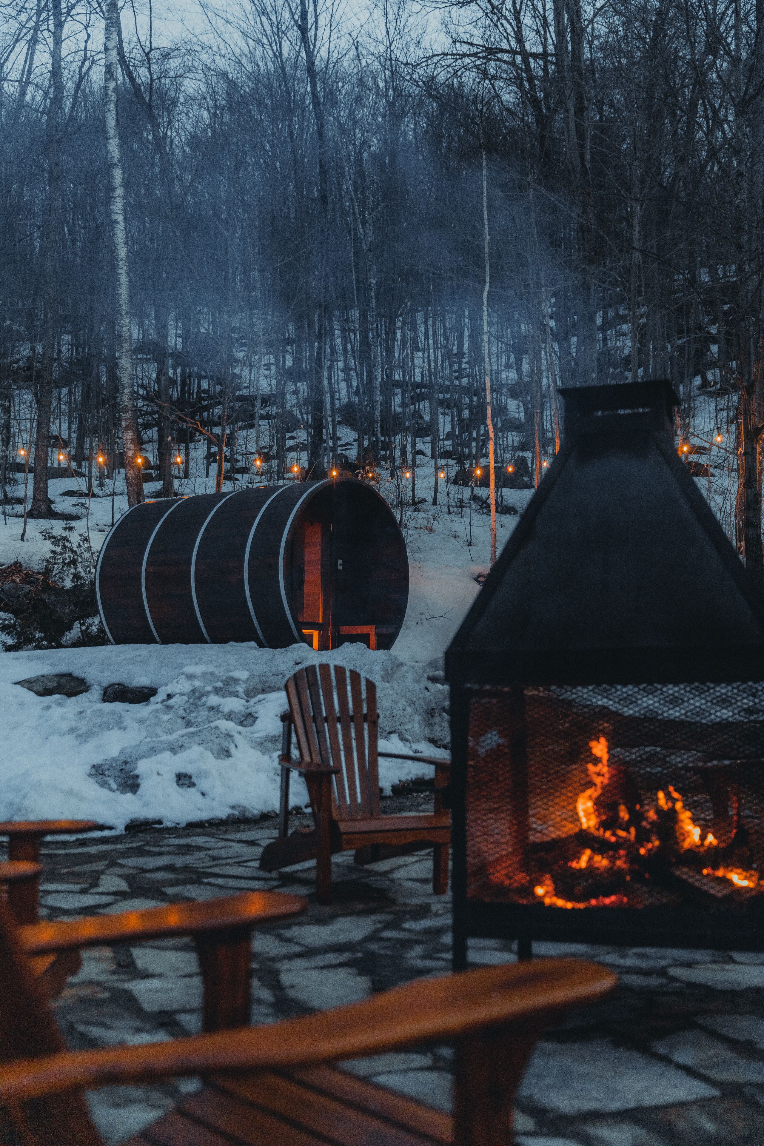 A rustic outdoor seating area with wooden chairs and a fire pit.