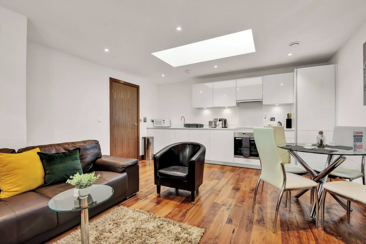 A modern living room with a sofa, coffee table, and a dining area with chairs and a table.