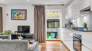 A modern living room with a flat-screen TV, grey sofas, a coffee table, and a painting on the wall.